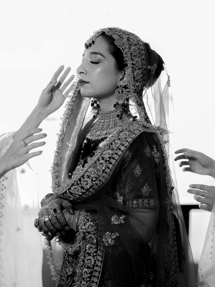 A powerful black and white portrait of the bride, her hands held in prayer, capturing the spiritual and emotional depth of the moment.