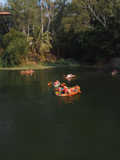 A wide shot of the lake with multiple groups enjoying boating and kayaking under a clear sky.