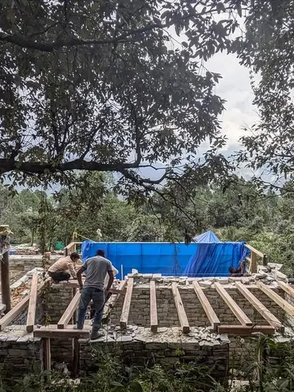As the monsoon rains subside, protective covers are removed to reveal the stone walls of our Himalayan guesthouses. The timber roof rafters are in place, ready for the next stage of construction.