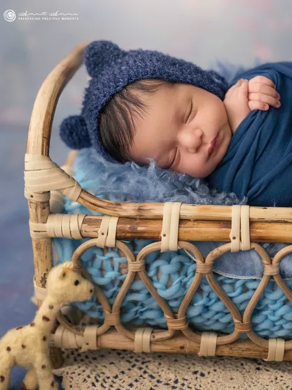 A sweet little bear in a basket. The knit bonnet with ears and the cozy blue tones make this an incredibly adorable and heartwarming portrait.