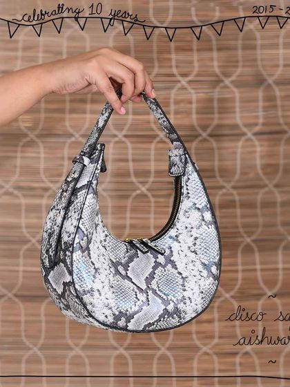 The Aishwarya crescent bag in our bold Disco Safari leather. This exotic, foiled snakeskin print gives the elegant, firm-bodied shoulder bag a modern and glamorous edge, perfect for day or evening wear.