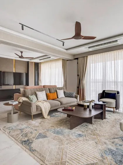 A comfortable and welcoming living room from our Urban Tranquility project. The space combines a neutral sofa with pops of color in the cushions, a large area rug, and sheer curtains to soften the abundant natural light.
