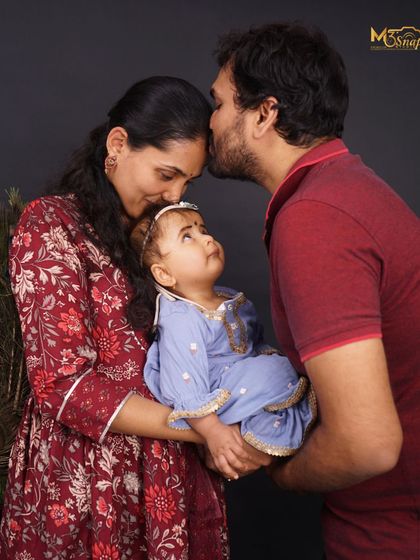 A slightly different angle of a beautiful family moment. The baby looks up towards her father, creating a sweet and engaging interaction within the portrait.
