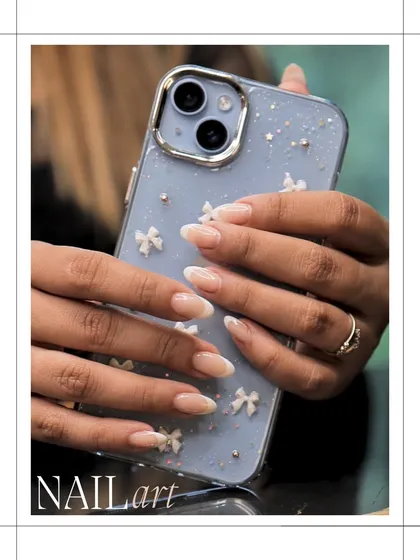 A delicate and feminine nail art design. This look features a sheer nude base with a subtle French tip and tiny, dainty bow embellishments for a sweet, charming finish.