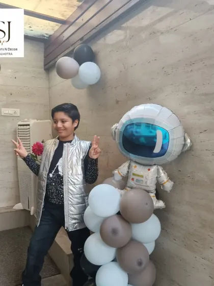 The birthday boy posing with an astronaut foil balloon at his space-themed party.