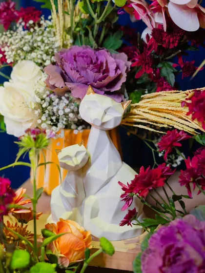 A whimsical touch with these geometric cat figurines nestled among a lush arrangement of purple and white flowers. It’s these unique details that make a setup memorable.