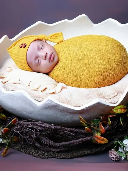A unique and whimsical setup featuring a newborn nestled inside a large, custom-made eggshell prop. This 'new life' theme is a creative way to celebrate your baby's arrival.