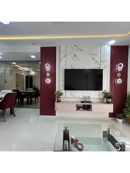 A closer look at the statement TV wall, which combines a marble-finish backdrop with rich burgundy panels and bespoke wall sconces. This feature serves as the focal point of the room.