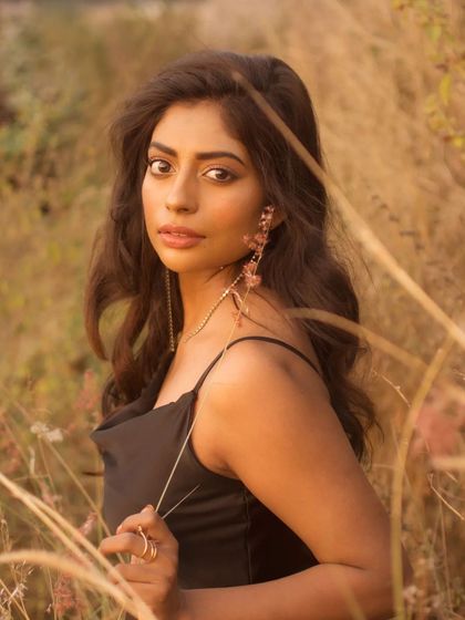 A direct and engaging portrait from the same field session. The subject holds a piece of grass, adding a natural, interactive element to the shot.