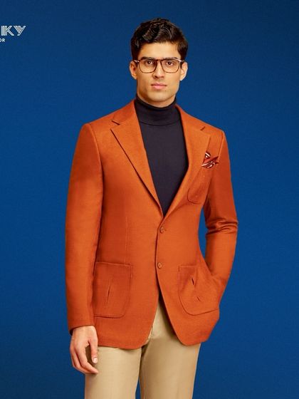 This vibrant orange blazer with patch pockets is designed to exude timeless elegance. Paired with a turtleneck, it creates a sophisticated look for any chic soirée.