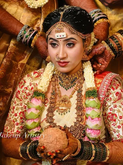 This is a powerful moment from a traditional South Indian wedding. The makeup is designed to be both divine and photogenic, highlighting her features amidst the rich colors of the ceremony.
