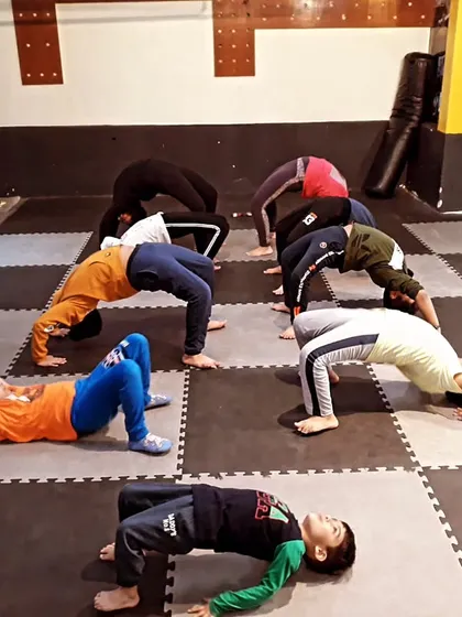 A warrior needs focus and a strong core. We mix in yoga and flexibility training to improve balance, prevent injuries, and calm the mind. Look at the determination in these kids holding the wheel pose.