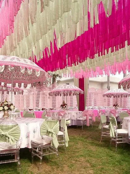 A wide view of the pink and mint green Mehendi, showing the beautiful interplay of colors in the drapes, umbrellas, and table settings.