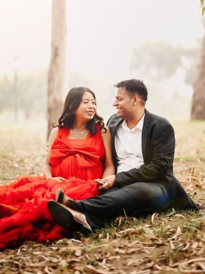 An intimate moment with an expecting couple sitting on the ground in a misty park. The soft focus and natural setting create a dreamy and romantic atmosphere for a maternity shoot.