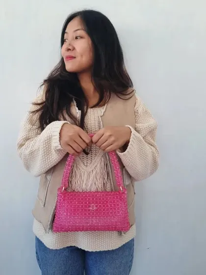A closer look at the hot pink beaded bag. You can see the uniform texture of the beadwork and the simple, elegant design of this shoulder bag. It's a perfect accessory to add a pop of color to an outfit.
