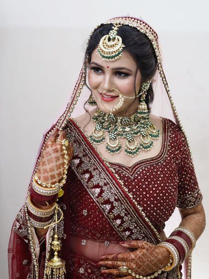 A happy bride posing in her complete rental look. The maroon lehenga with silver embroidery and the heavy green Kundan set is a classic and popular choice.
