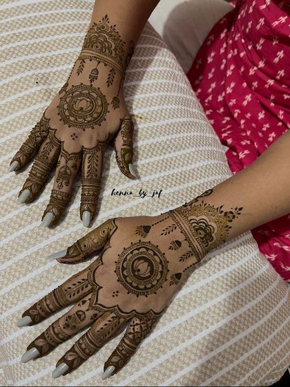 The completed bridal henna for a client, showcasing matching mandala designs on both hands. The intricate patterns extend from the wrist to the fingertips.