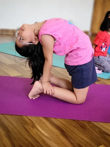 A young student explores Ustrasana, the camel pose, a heart-opening backbend that builds confidence and flexibility. It is so rewarding to see their happy faces as they discover new abilities each week.