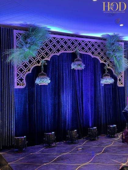 A still shot of the musician's stage, with dramatic blue lighting highlighting the intricate details of the arch and hanging decor.