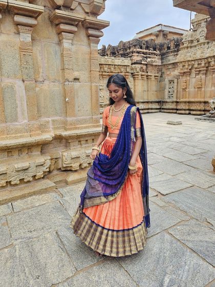 A young client wearing a traditional half-saree in peach and navy blue, perfect for temple visits or family functions.