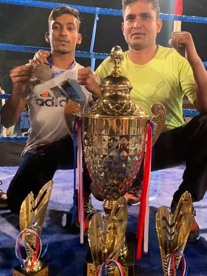 Another one of our champions with his coach and trophy. The bond between a coach and a fighter is key to success.