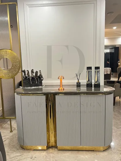 A custom console table with a unique, split-level design. The piece features a grey fluted body, a marble top, and a central accent in a high-shine gold finish, making it a sculptural and eye-catching item.