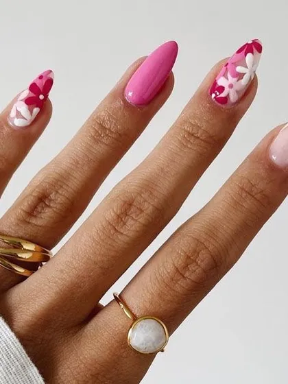 A beautiful floral manicure combining solid pink nails with accent nails featuring a delicate flower pattern. This design is perfect for a feminine and sophisticated style.