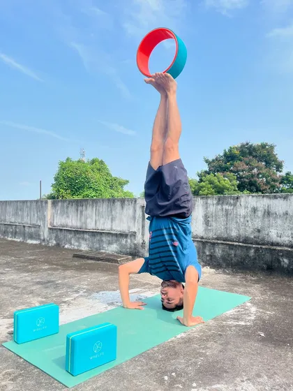 I use props like the yoga wheel to help students deepen their practice and achieve advanced poses like this headstand variation. My yoga classes focus on building balance, core strength, and proper alignment.