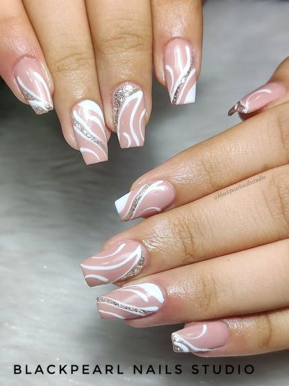 A beautiful set of nude nails with white swirl art and a touch of silver glitter. This design is elegant and glamorous, perfect for a special occasion.