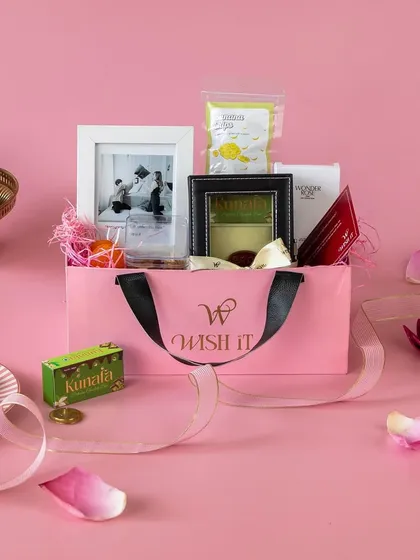 Introducing our "Rakhi Bloom Bag", a festive and nostalgic hamper in a lovely blush pink bag, perfect for making your sibling feel special.