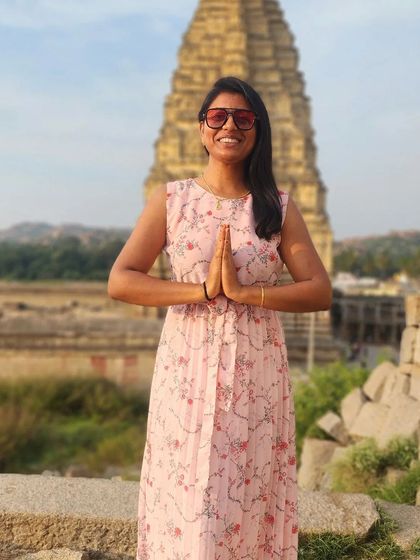 A traveler in a prayer pose in front of a temple in Hampi, capturing a moment of peace and devotion.