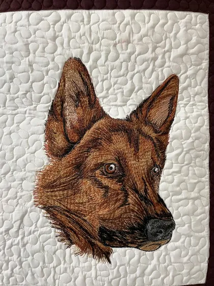 A close-up of the German Shepherd portrait from the dog-themed art quilt, showing the detailed thread painting.