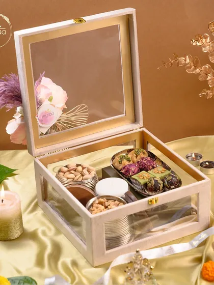 This sophisticated white wooden box with glass panels is perfect for Diwali. It's filled with an assortment of my finest gourmet mithai and premium nuts for a truly luxurious gift.