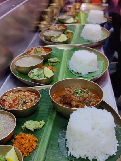Our thalis getting ready to be served at a busy pop-up. Each plate is carefully assembled with a mound of Indrayani rice, different curries, and fresh accompaniments, all served on a traditional banana leaf for that authentic touch.