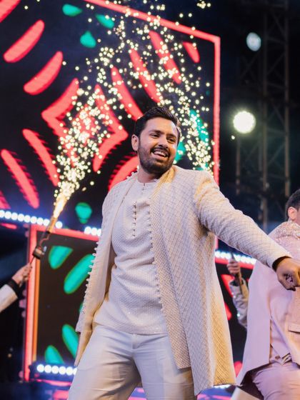 The groom making a grand entrance at his sangeet, his layered ivory outfit perfect for a night of dancing.