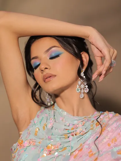 The bright blue eyeshadow provides a stunning pop of color against the pastel outfit.