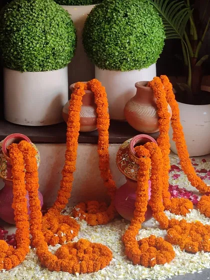 This corner decoration uses several small matkas with marigold garlands flowing out of them. The floor is scattered with fresh flower petals, creating a lovely and detailed display.