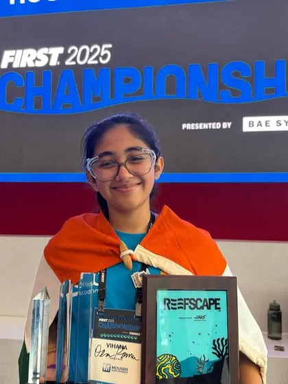 Vihaana Desai, draped in the Indian flag, holds the team's awards. This powerful image symbolizes our achievement of representing India and winning at the highest level of international school robotics.
