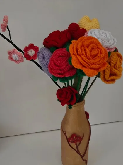 A full view of a mixed crochet flower bouquet in a decorative vase. This arrangement shows the variety of colors and flower types I can create to match any decor style.