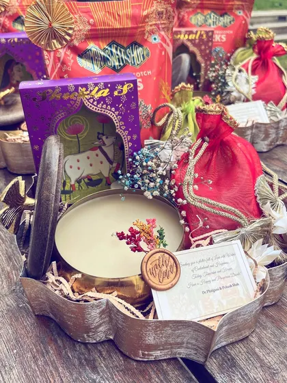 Radiating positivity for Diwali. This hamper, curated in a rustic metal container, features a mix of traditional sweets, colorful potlis, and a personalized note sealed with wax for a truly bespoke touch.