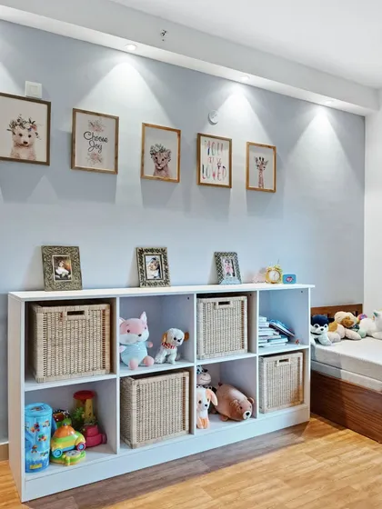Another view of the toy storage area, with soft spotlights highlighting the gallery wall of cute animal prints. The setup is both adorable and functional.
