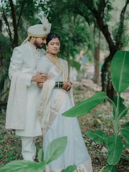 A classic portrait of the couple in a lush, green setting. The groom's arm around the bride conveys a sense of protection and love.