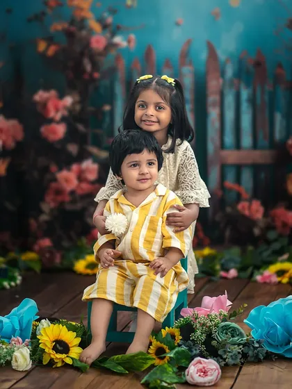 A sweet portrait of a brother and sister in our floral garden setup. The older sister's gentle embrace is a testament to their loving bond.