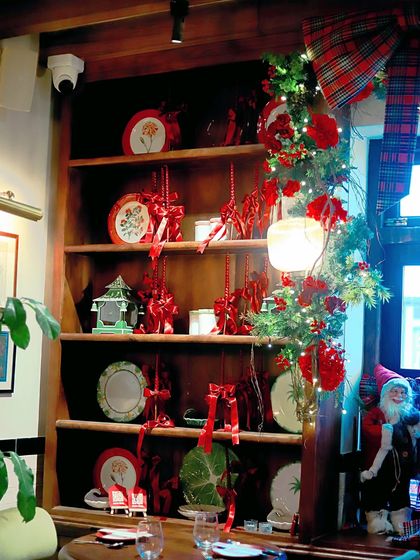 Shelves decorated with festive plates, red ribbons, and garlands of greenery and lights.