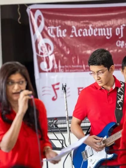 A teacher sings alongside a student guitarist, demonstrating our hands on approach to coaching during live performances.