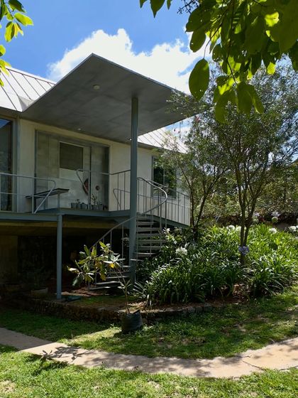 An outdoor staircase and cantilevered roof at the 'Wildgrass' home. These elements create sheltered outdoor living spaces that are integrated with the garden, blurring the lines between inside and out.