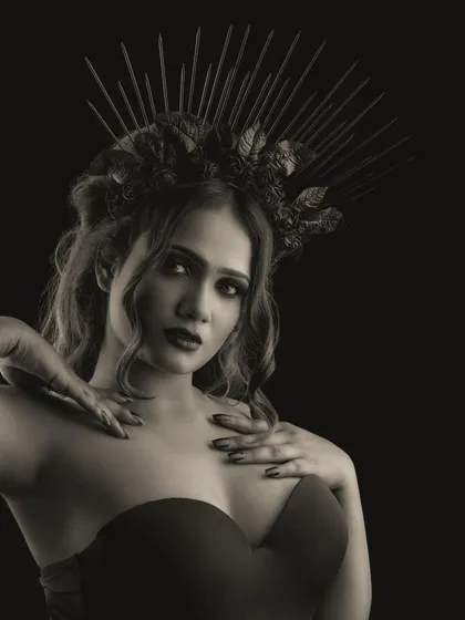 A monochrome portrait of the dark queen character. The black and white format emphasizes the contrast of the dark makeup and the model's intense gaze, highlighting the dramatic effect of the look.