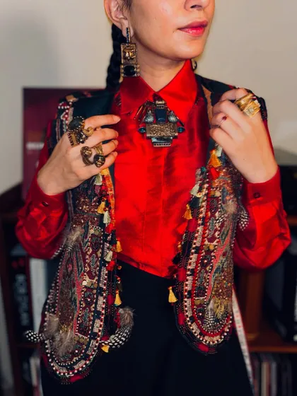 A detailed shot of the couture week look, focusing on the intricate vest and layered statement jewellery.
