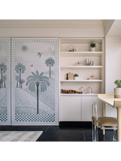 The home office lounge is a multi-tasking space that evolves from a family room to a work-from-home area. Tropical botanical wallpaper panels conceal the TV, blending function with nature-inspired beauty.