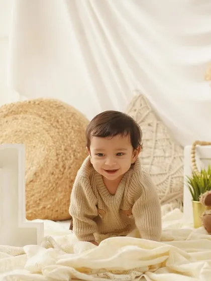 A candid shot of a baby boy crawling towards the camera during his cozy, teddy-bear themed first birthday photoshoot.